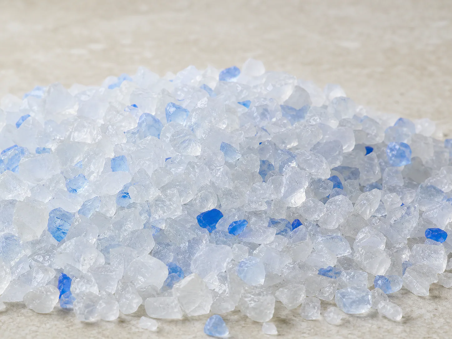 Close view of clear silica gel cat litter crystals with pale blue indicator pieces